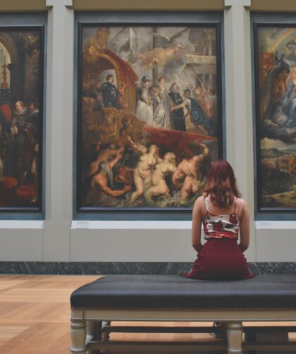 woman-sitting-on-ottoman-in-front-of-three-paintings