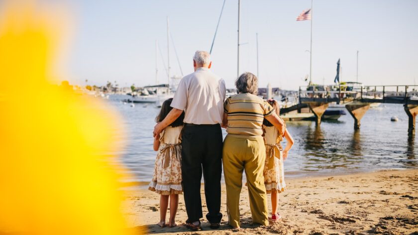 grandparents-with-their-granddaughters-standing-by-the-shore